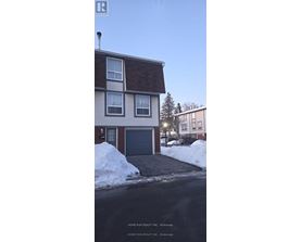 A two-story house with a garage and a driveway covered in snow.