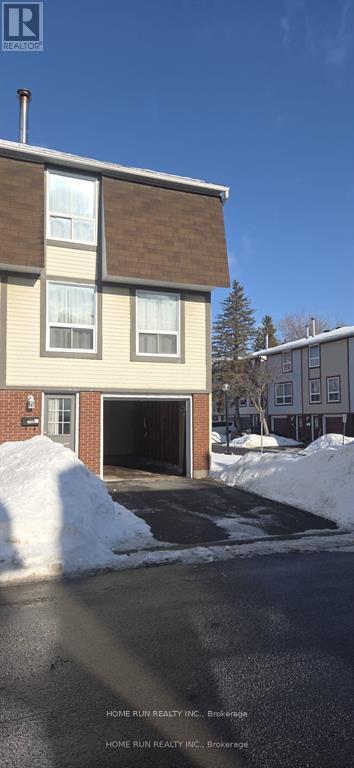 A two-story house with a garage and a driveway covered in snow.
