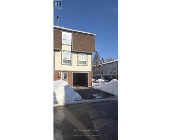 A two-story house with a garage and a driveway covered in snow.