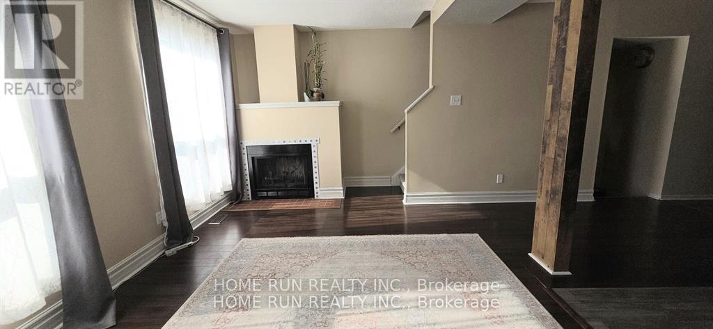 A living room with a fireplace and a rug on the floor.