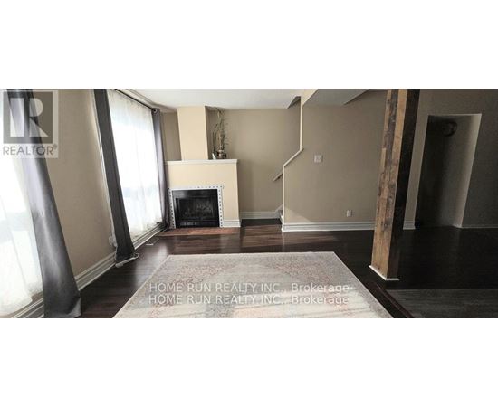 A living room with a fireplace and a rug on the floor.