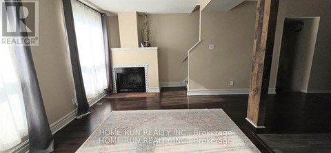 A living room with a fireplace and a rug on the floor.