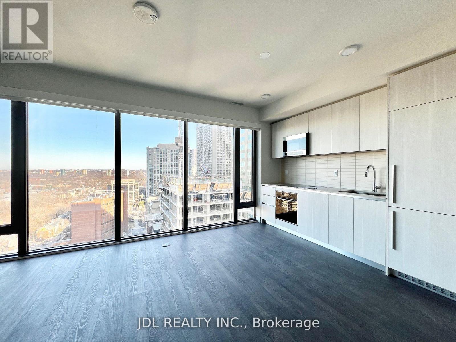 A spacious room with a view of the cityscape through large windows.