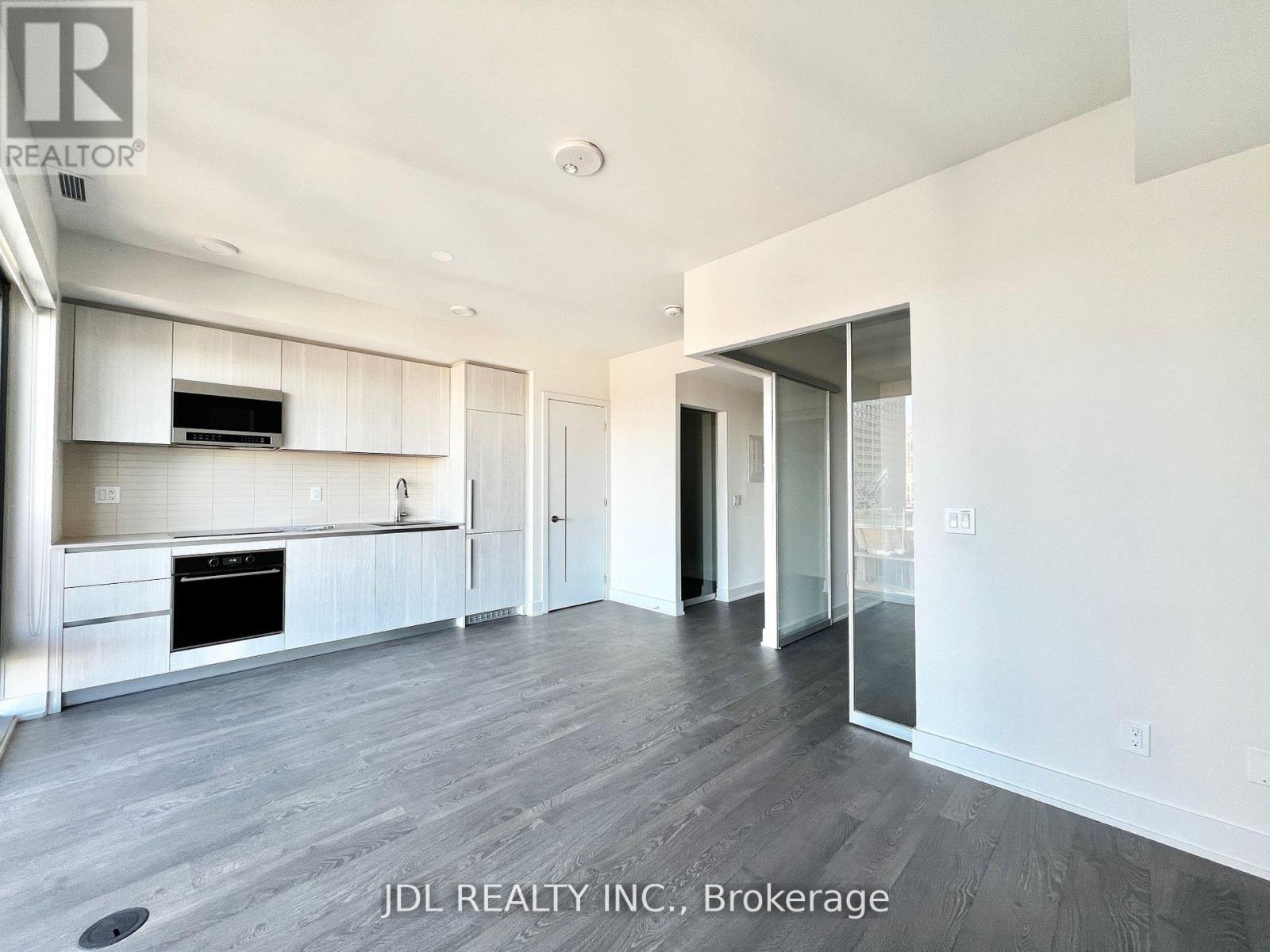 A spacious kitchen with white cabinets and a wooden floor.