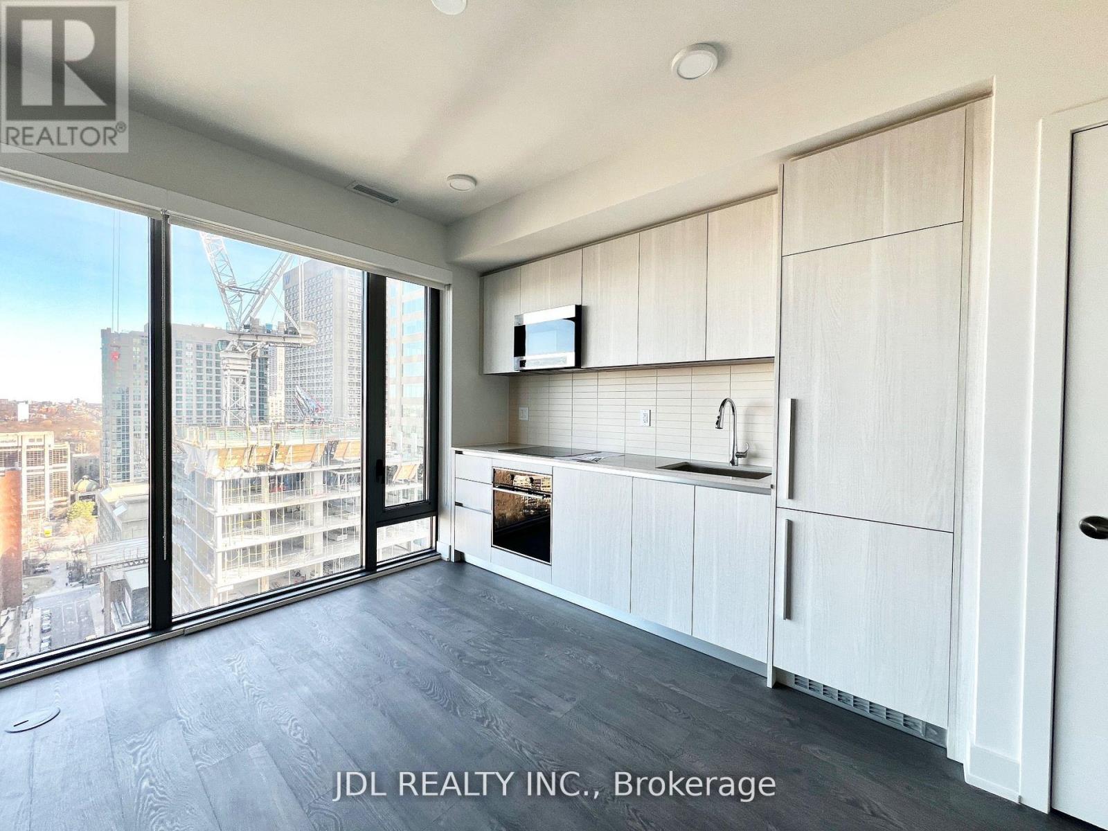 A kitchen with white cabinets and a large window overlooking a cityscape.