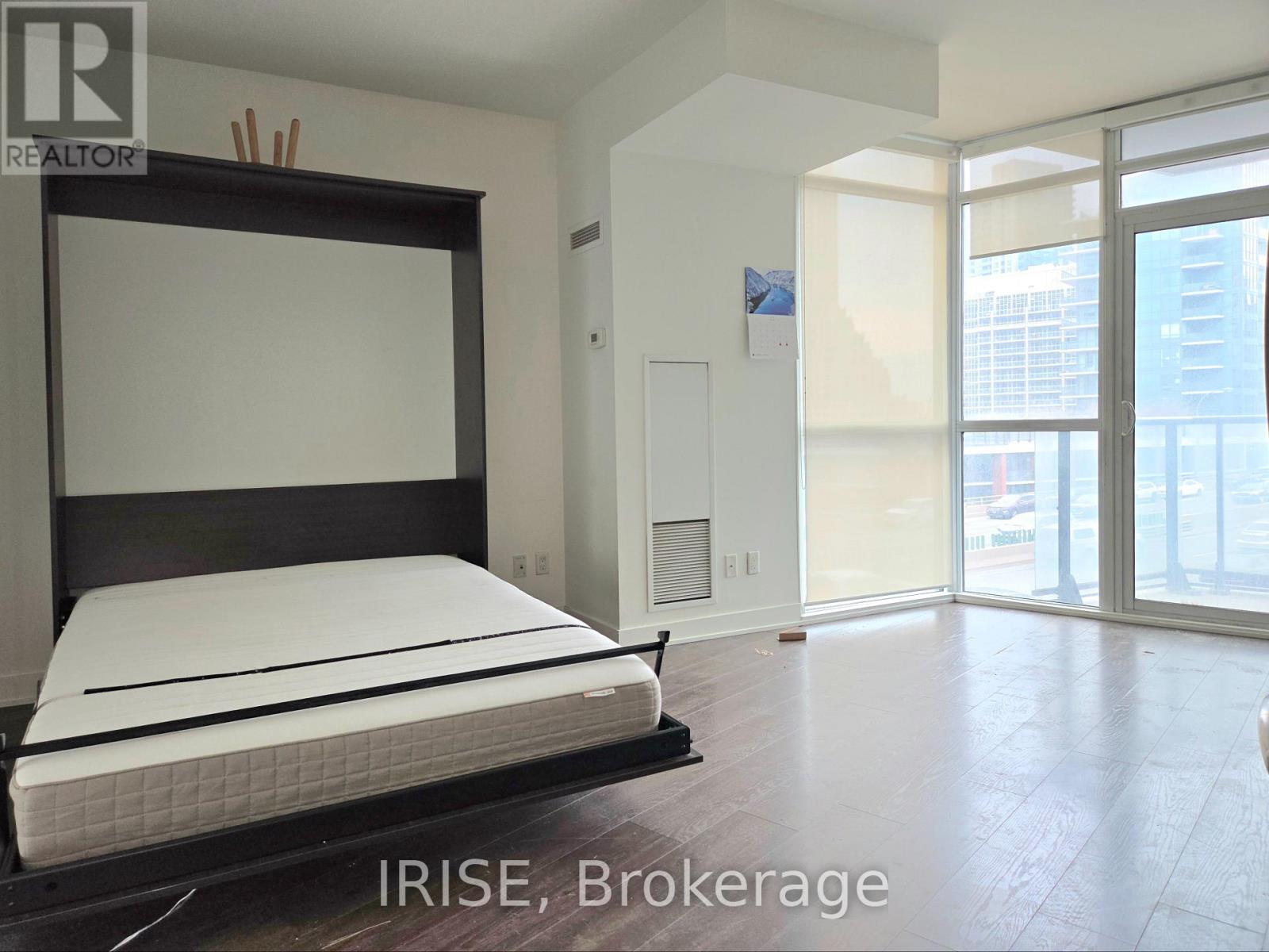A bedroom with a large bed and a sliding glass door.