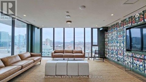 A living room with a brown leather couch and a large window overlooking the city.