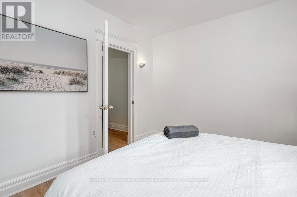 A bedroom with a white bed and a painting on the wall.