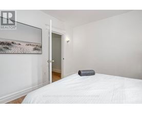 A bedroom with a white bed and a painting on the wall.