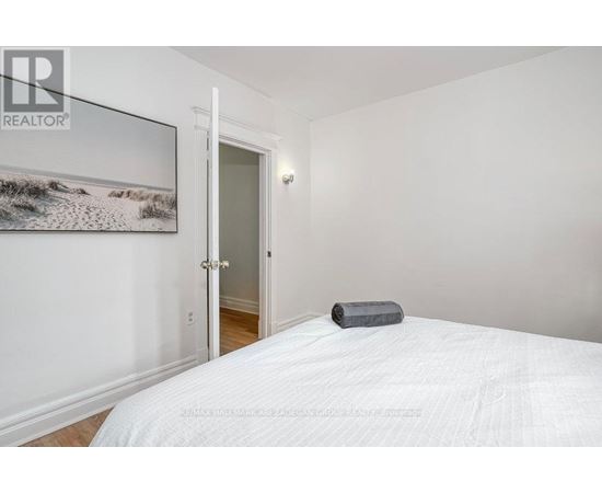 A bedroom with a white bed and a painting on the wall.