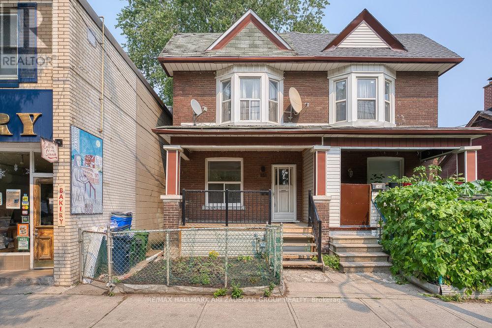 A house with a brown roof and a white door is in front of a building with a sign that says "REALTOR".