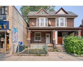 A house with a brown roof and a white door is in front of a building with a sign that says "REALTOR".