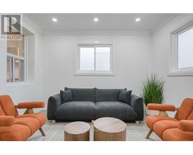 A living room with a grey couch, orange chairs, and a wooden coffee table.