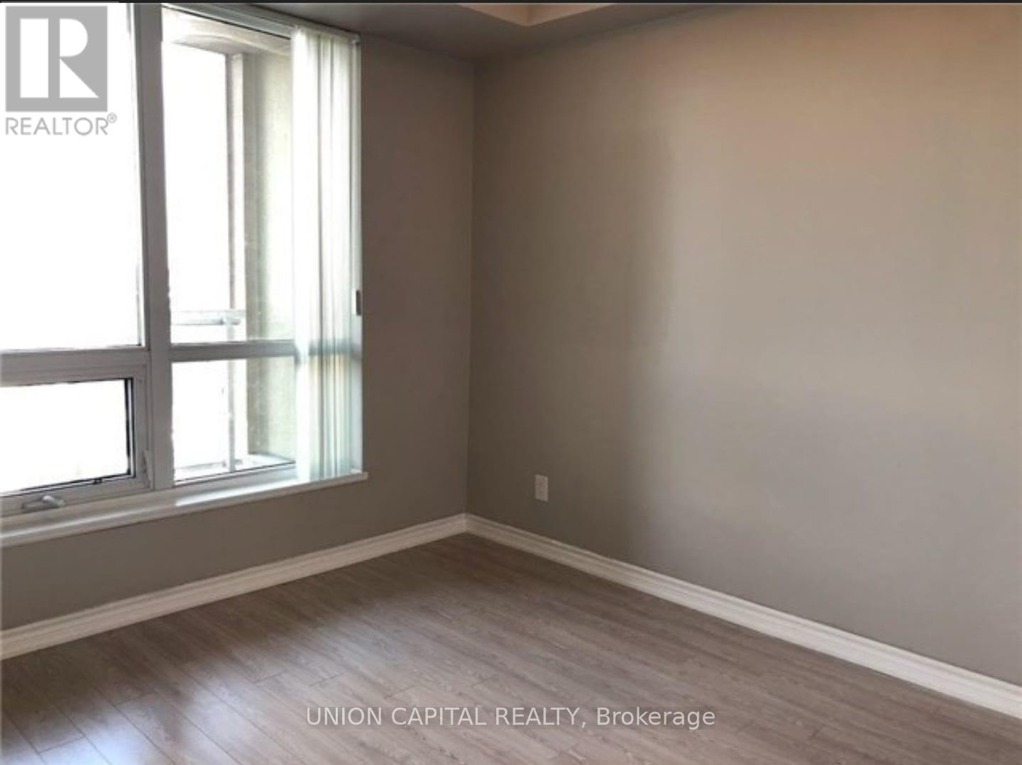 A room with a window and wooden flooring.