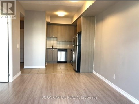 A kitchen area with a refrigerator, sink, and cabinets.