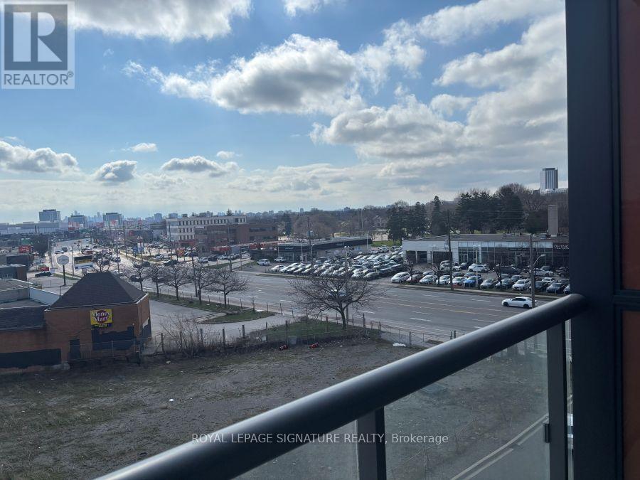 A view from a balcony looking out over a parking lot and buildings.