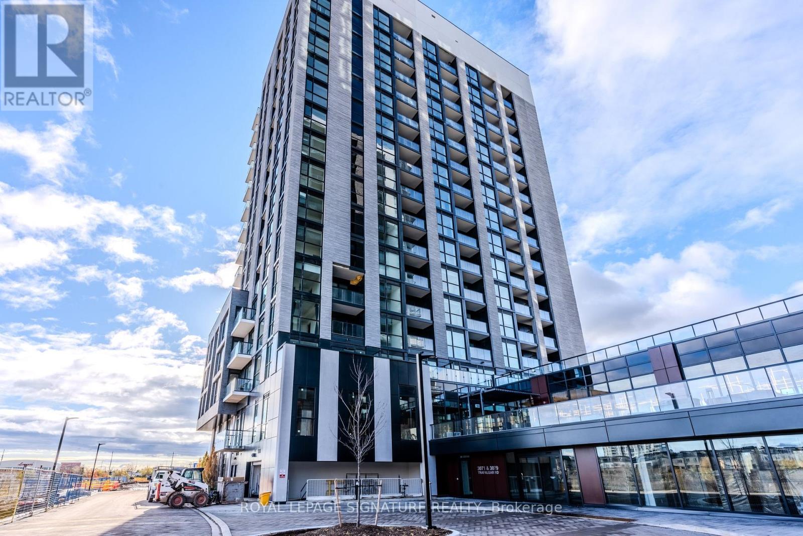 A tall building with a glass facade stands under a blue sky.