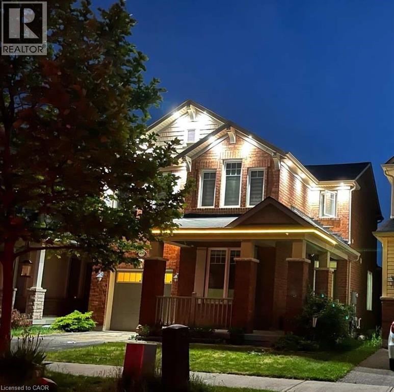 A house with a lit up front porch and a tree in front of it.