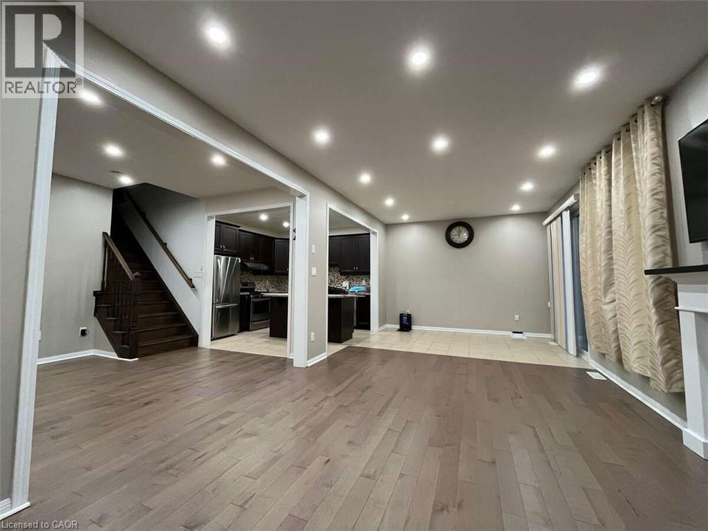 A spacious room with wooden flooring and a staircase leading to another level.