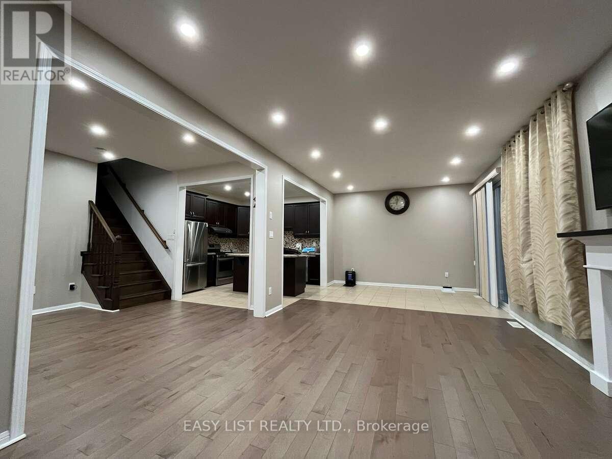 A spacious room with wooden flooring and a staircase leading to another level.