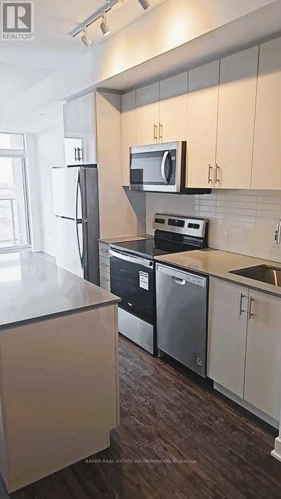 A kitchen with white cabinets and a black fridge.