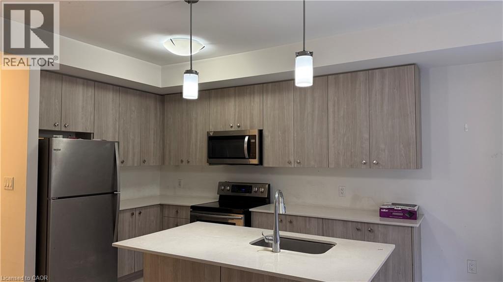 A kitchen with a refrigerator, microwave, and sink.