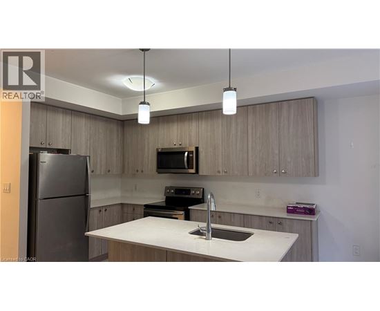 A kitchen with a refrigerator, microwave, and sink.