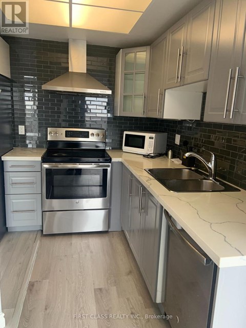 A kitchen with a stove top oven, microwave, and sink.