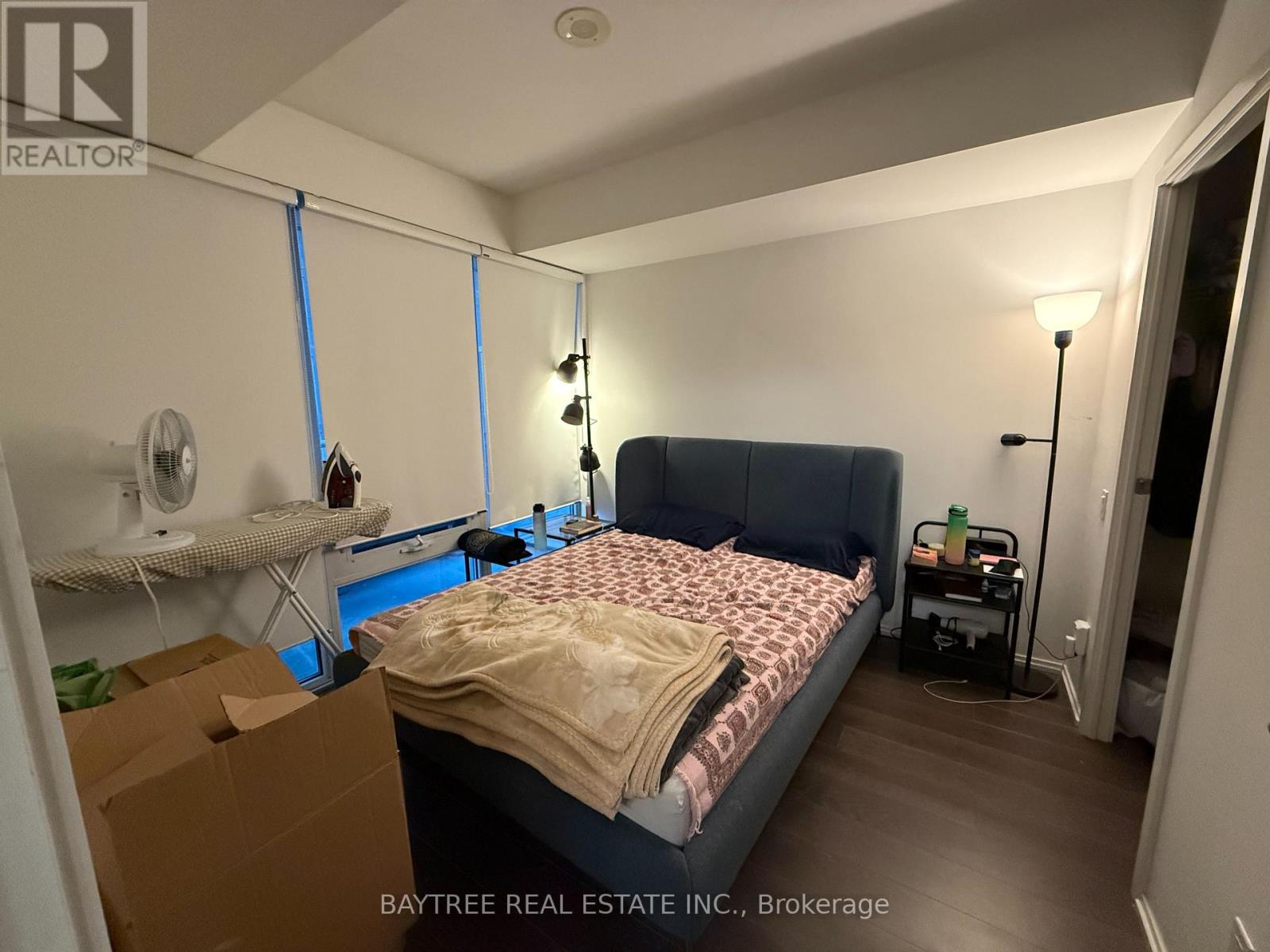 A bedroom with a bed, nightstand, and a window with curtains.