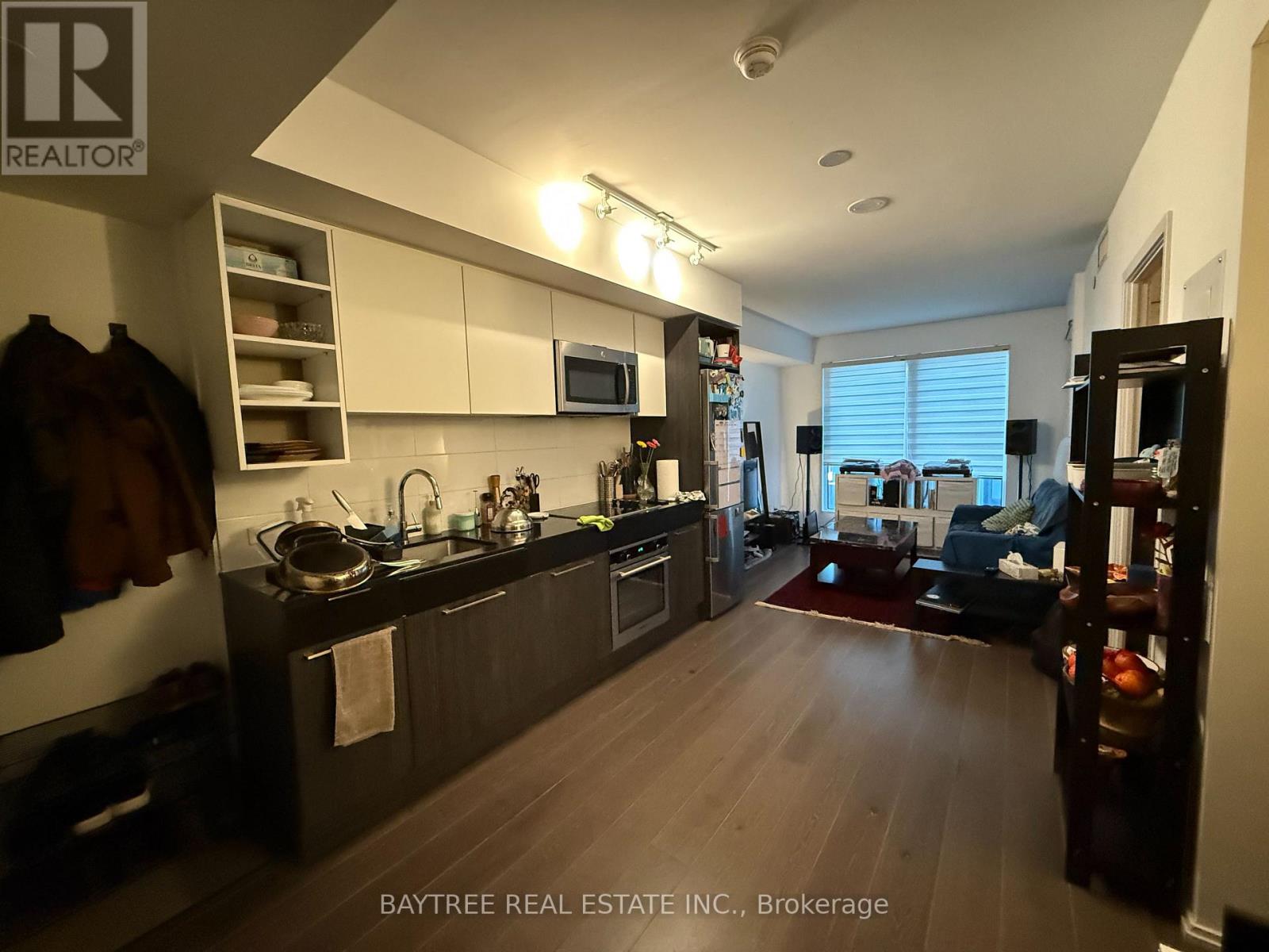 A well-lit kitchen with dark wood floors and modern appliances.