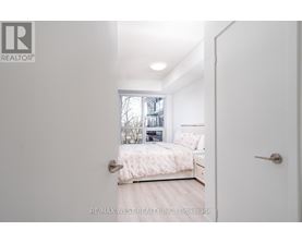 A bedroom with a bed, nightstand, and window.