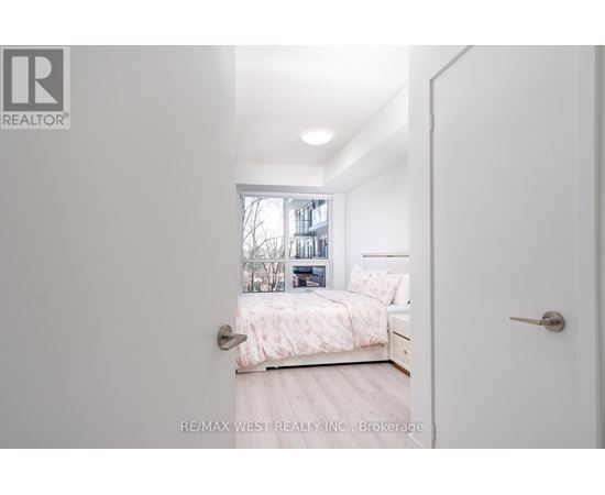 A bedroom with a bed, nightstand, and window.