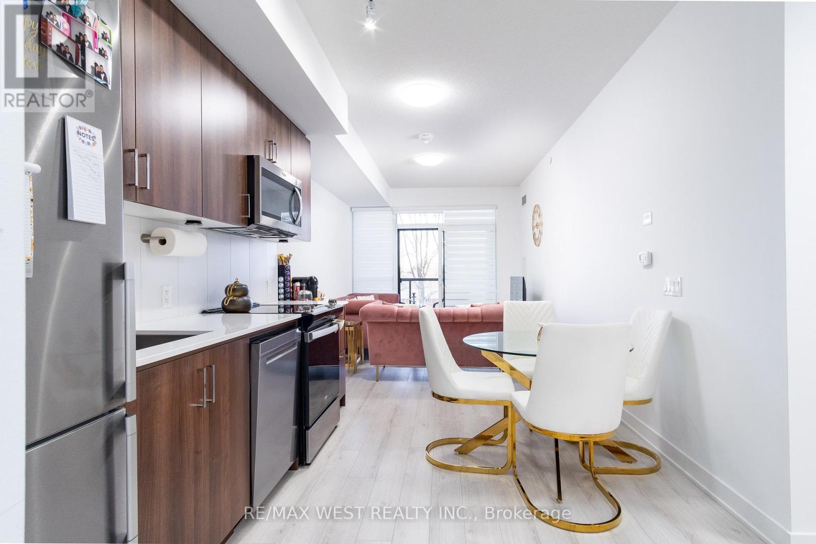 A kitchen with a refrigerator, microwave, and a dining table with chairs.