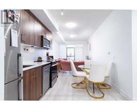 A kitchen with a refrigerator, microwave, and a dining table with chairs.