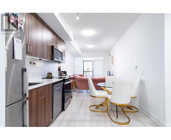 A kitchen with a refrigerator, microwave, and a dining table with chairs.