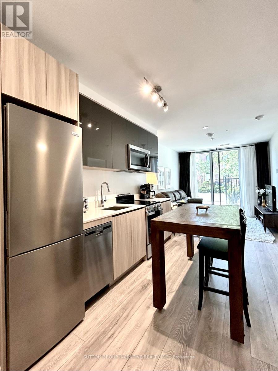 A modern kitchen with a stainless steel refrigerator and wooden flooring.