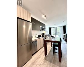 A modern kitchen with a stainless steel refrigerator and wooden flooring.