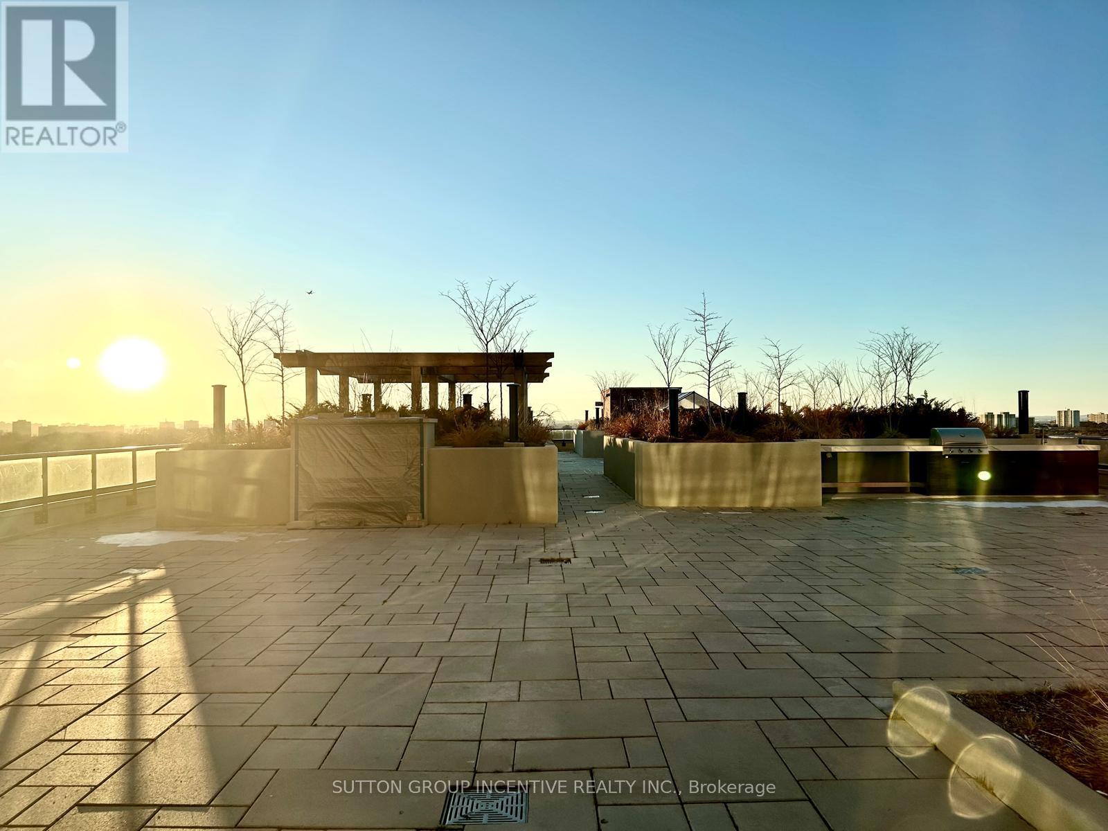 A sunset view of a paved area with a gazebo in the distance.