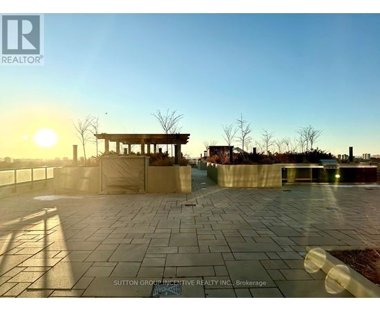 A sunset view of a paved area with a gazebo in the distance.