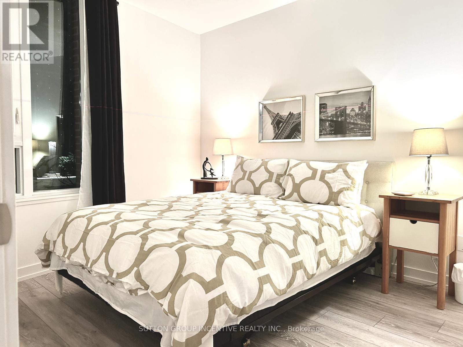 A bedroom with a large bed and a nightstand with a lamp.