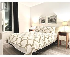 A bedroom with a large bed and a nightstand with a lamp.