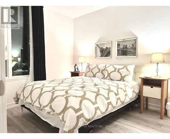 A bedroom with a large bed and a nightstand with a lamp.