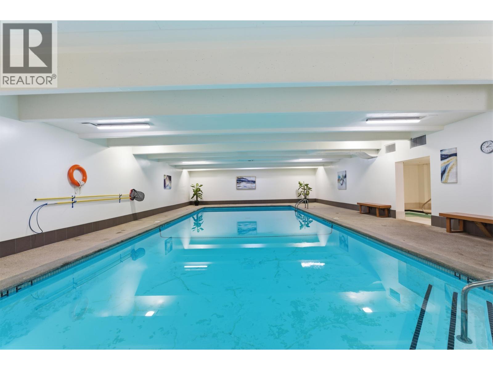 A swimming pool inside a building with a logo on the wall.