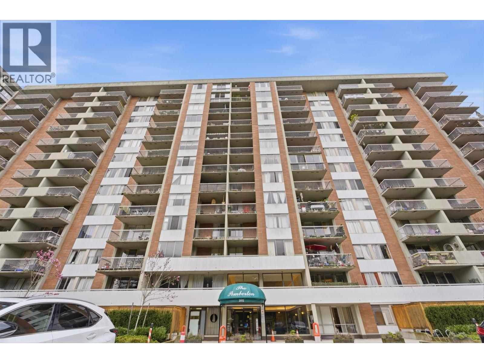 A tall apartment building with a green awning in front.