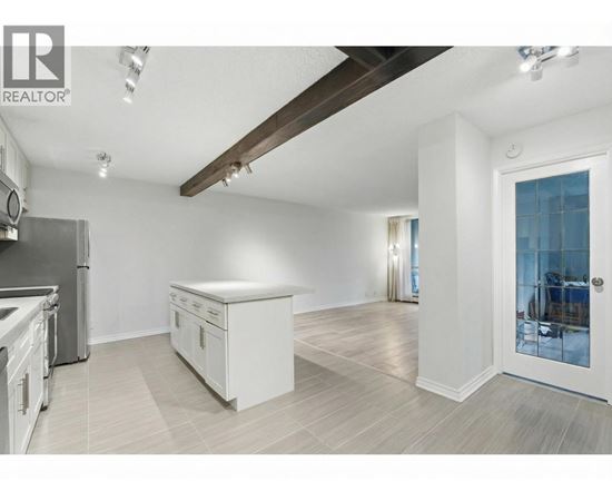 A spacious kitchen with white cabinets and a wooden ceiling beam.