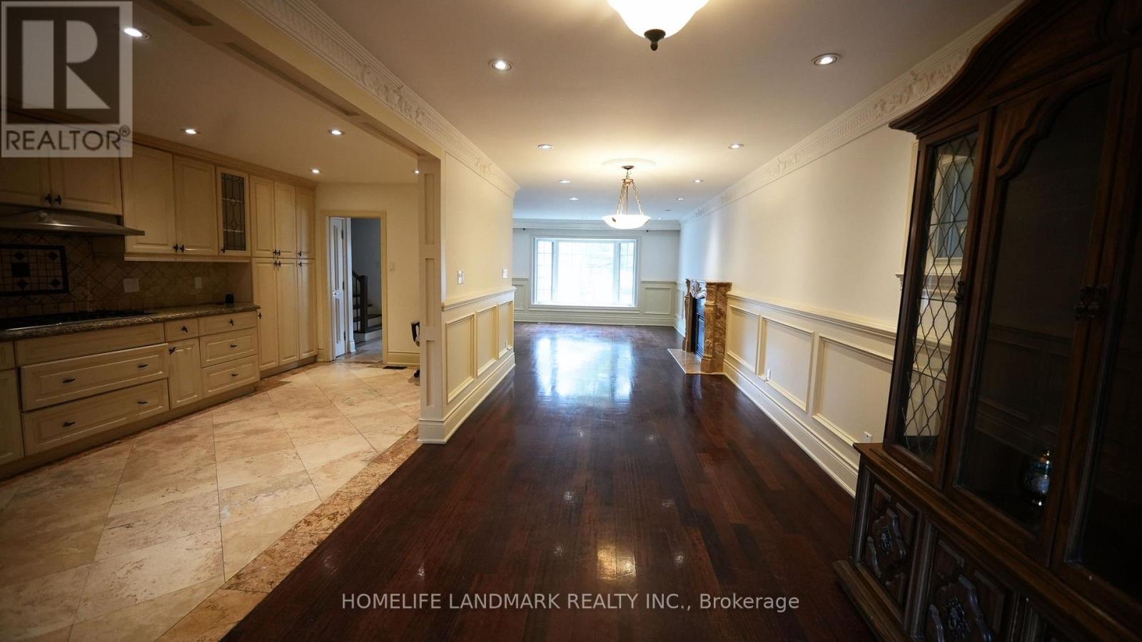 A spacious room with wooden floors and a kitchen area with a counter and cabinets.