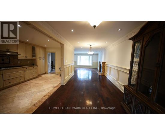 A spacious room with wooden floors and a kitchen area with a counter and cabinets.