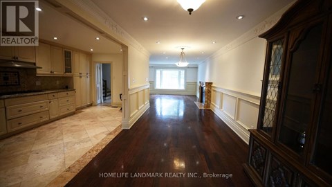 A spacious room with wooden floors and a kitchen area with a counter and cabinets.