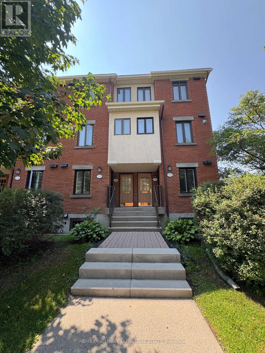 A red brick building with a beige trim and a set of stairs leading to the front door.
