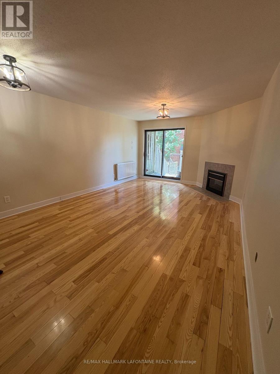 A spacious room with wooden flooring and a fireplace.